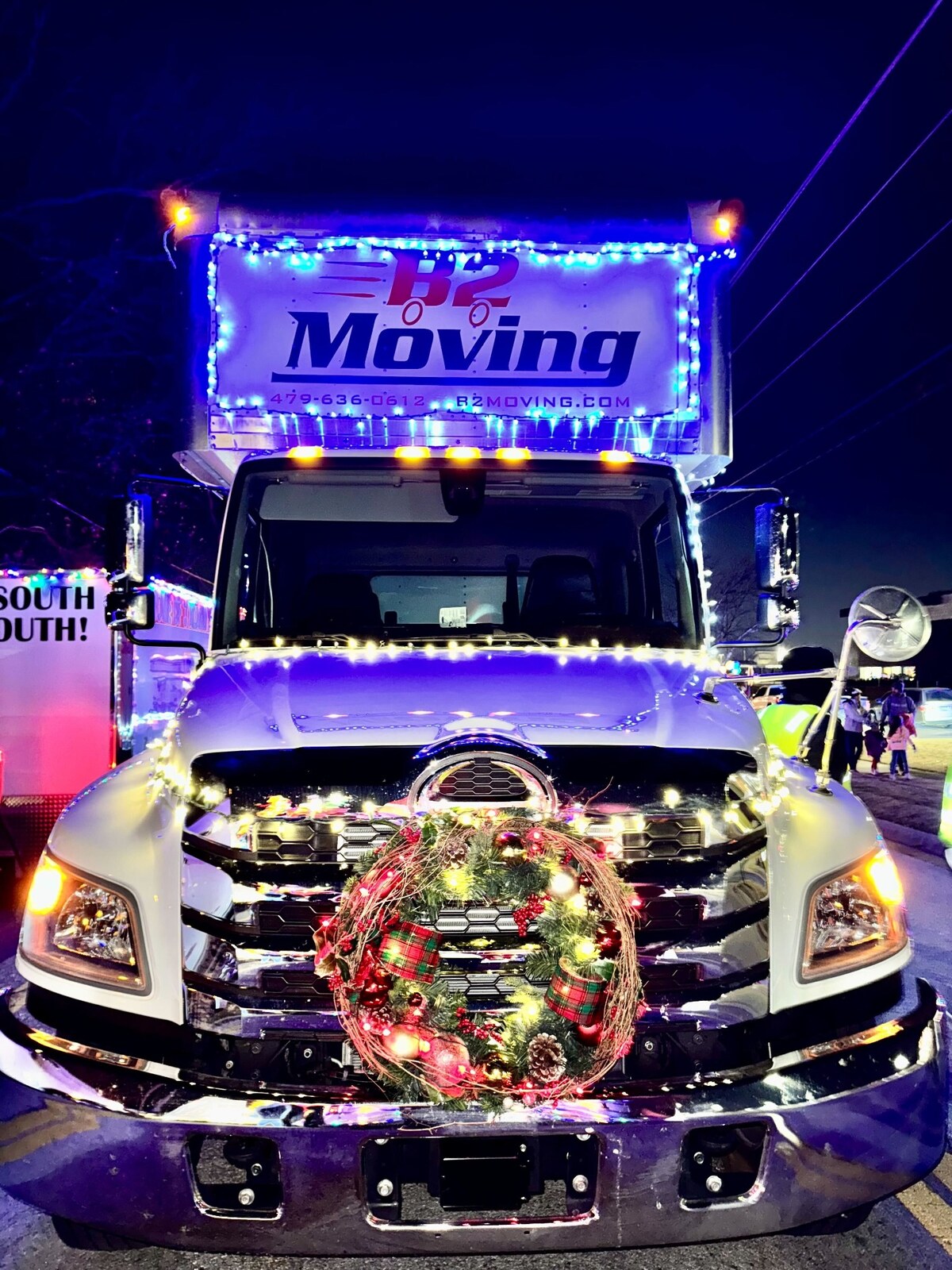B2 Moving truck decorated with Christmas lights and a wreath for the 2025 Bentonville Christmas Parade