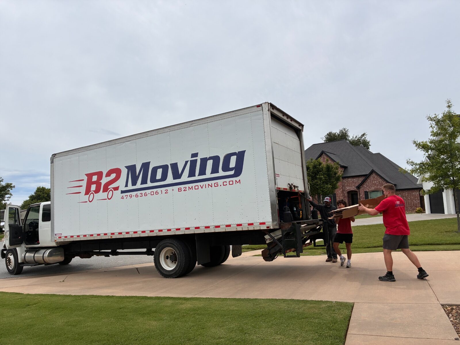B2 movers Noah, Jaxon, and Dolph working at the truck liftgate during a Bentonville to Rogers local move