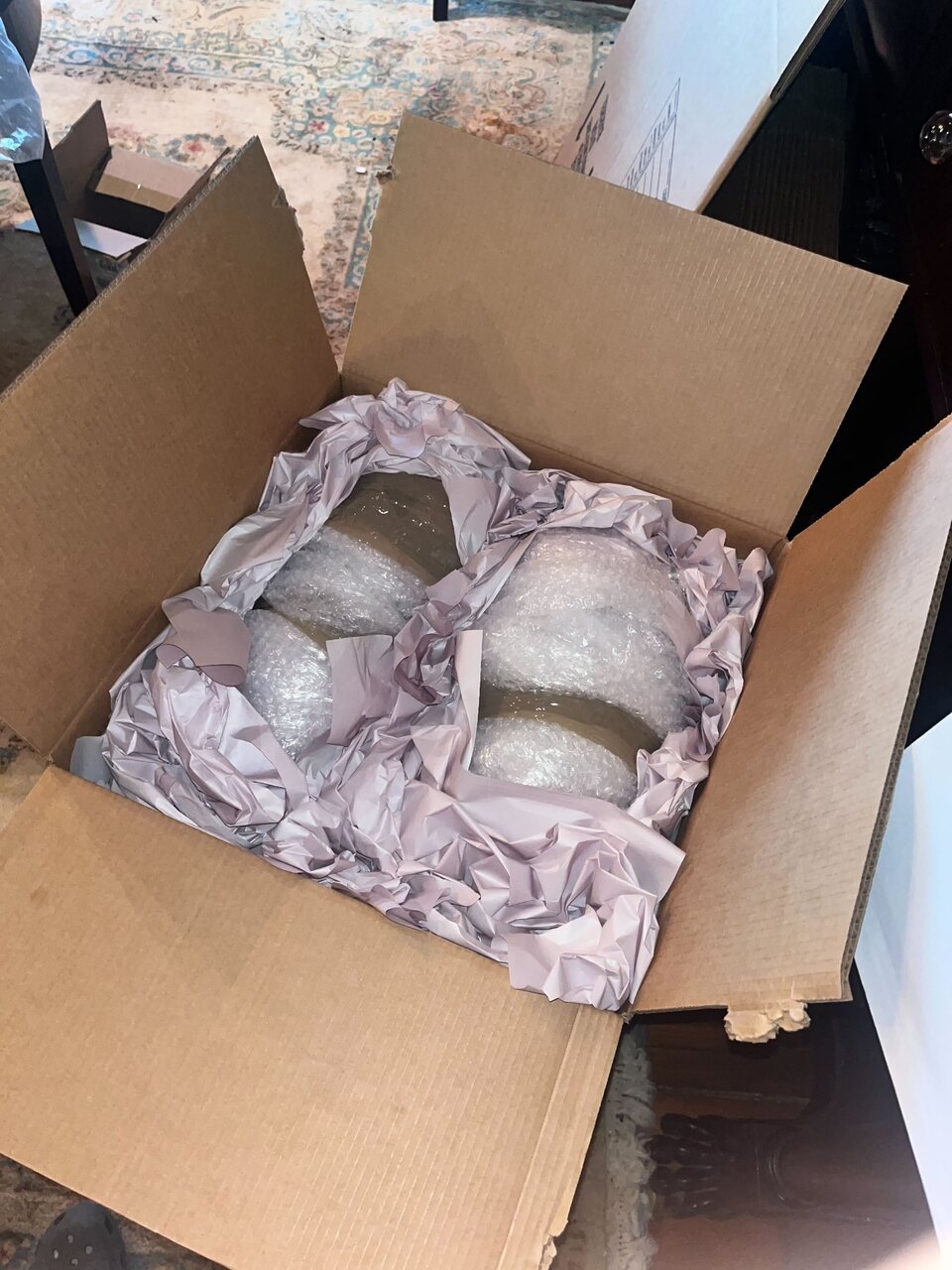 Fragile household items protected with bubble wrap, clean paper, and a sturdy box