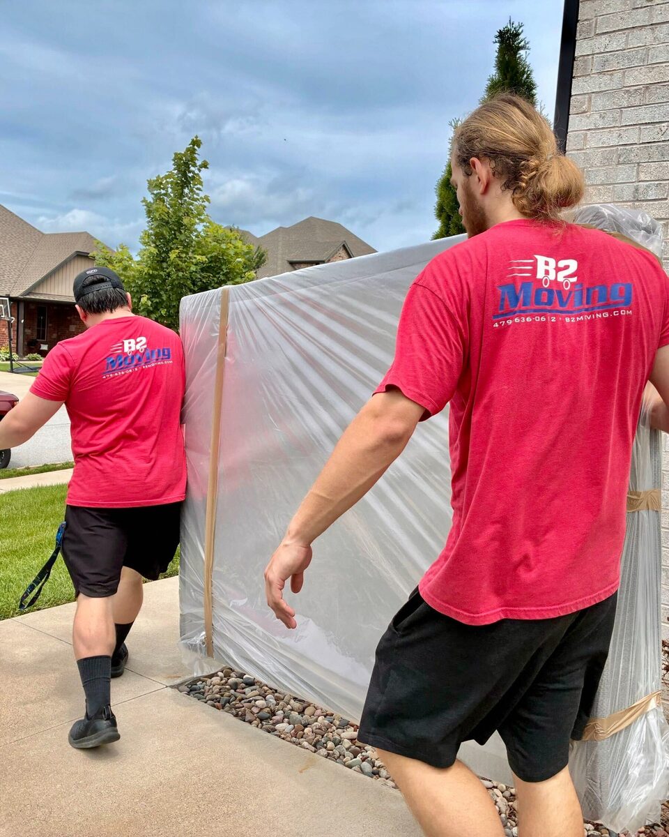 B2 Moving crew members Isaac and Traven carrying a mattress protected in a bag