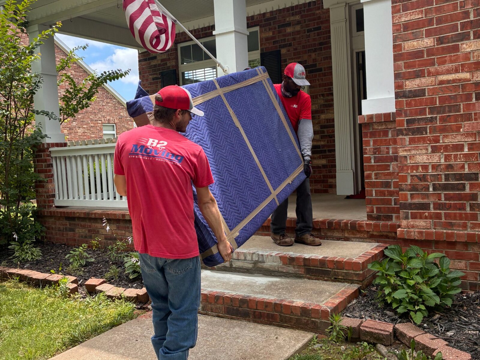 Jodie and Dolph carefully carrying a fully padded dining-table top during a Springdale move